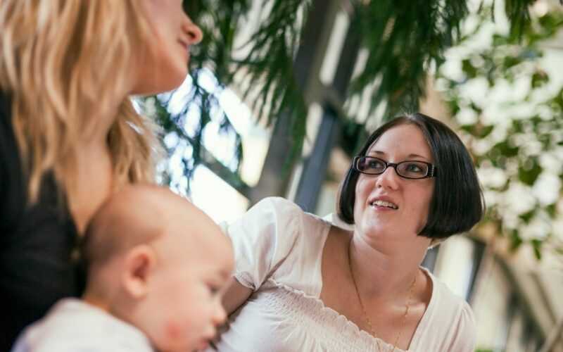twee vrouwen in gesprek met een baby op schoot