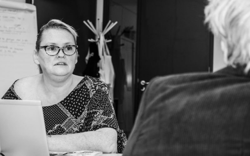 Vrijwilliger Silvia aan haar laptop in gesprek met een vrouw
