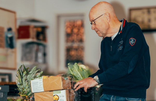 Vrijwilliger Gerrit bij dozen en kratten van de Voedselbank